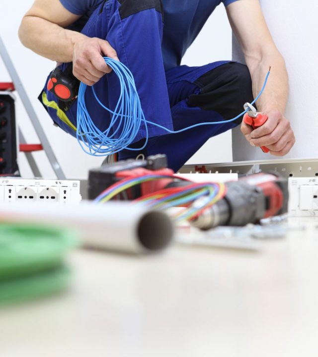 electrician at work with nippers in hand cut the electric cable, install electric circuits, electrical wiring